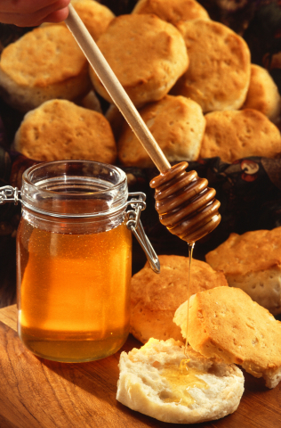 Honning overføres fra en glasskrukke til et rundstykke på delikat vis.