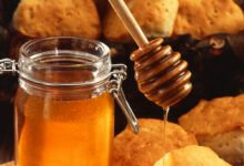 Honning overføres fra en glasskrukke til et rundstykke på delikat vis.